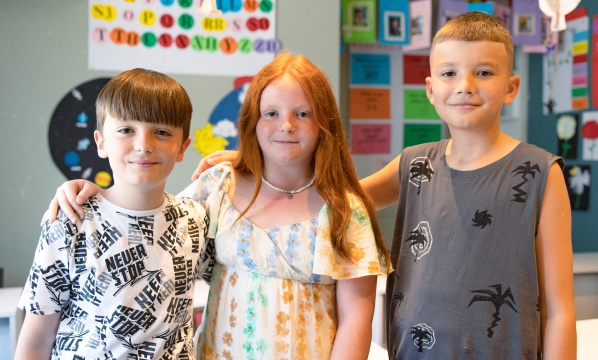 Three kids with hands over each other shoulders learning